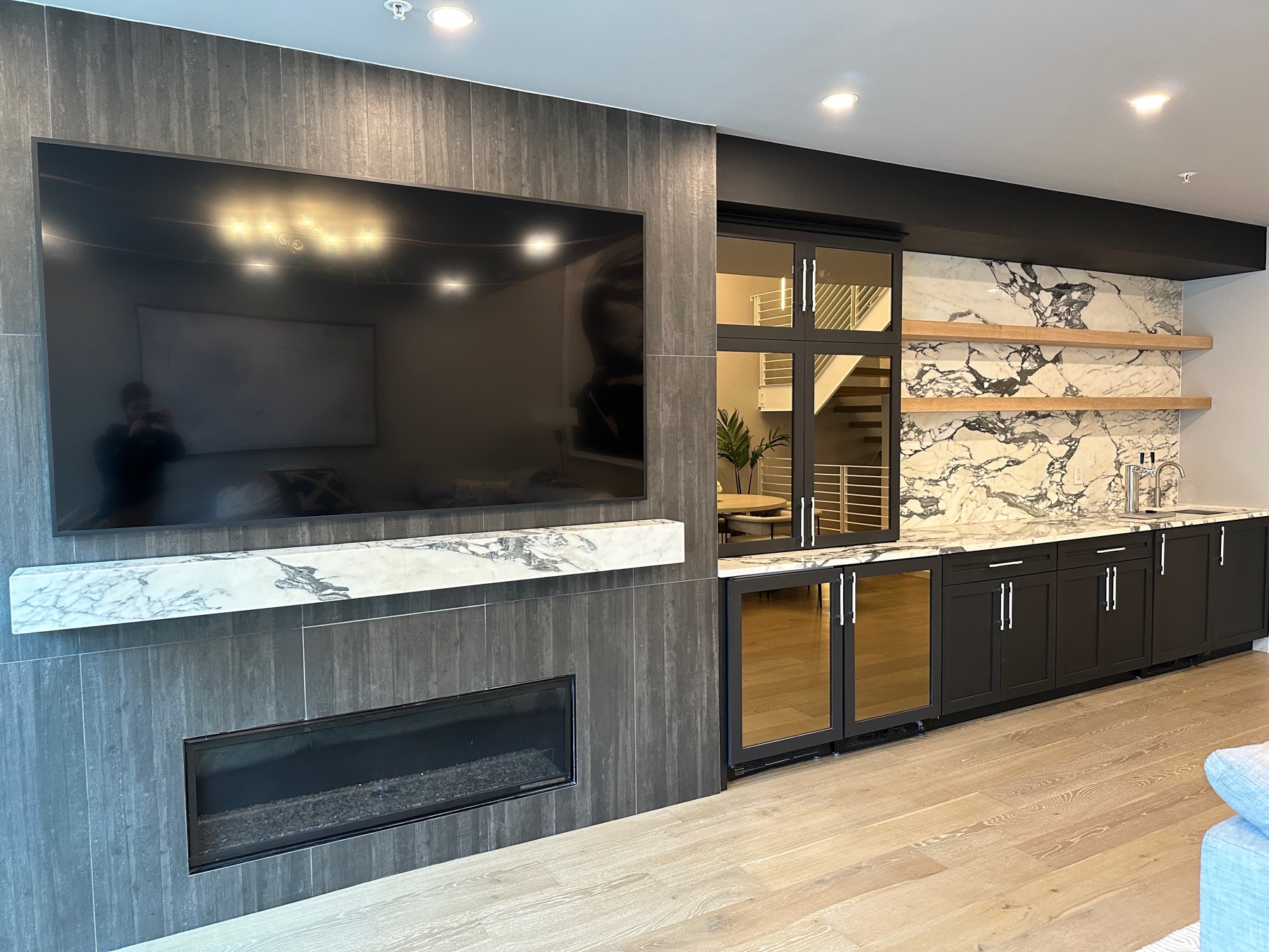 Marble wet bar and media wall with dark cabinetry