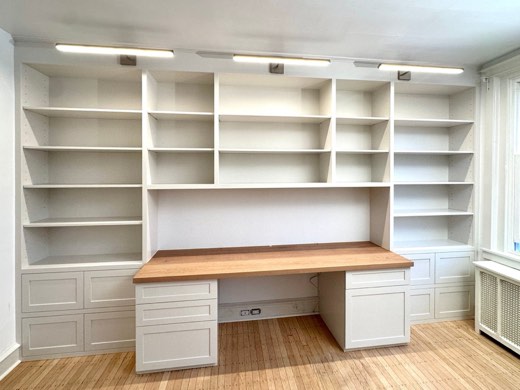 White home office wall of shelving with wood desk